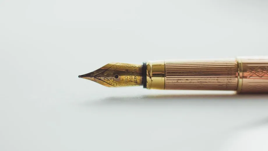A brass quill pen on a plain white backdrop